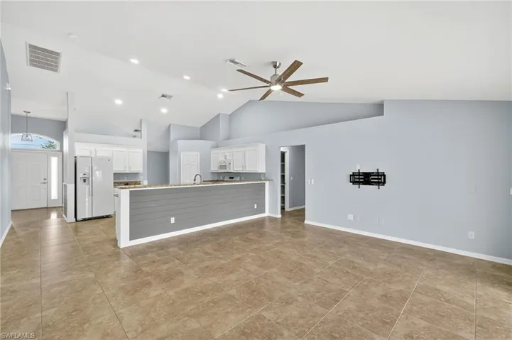 Unfurnished living room with high vaulted ceiling, a ceiling fan, recessed lighting, and light tile patterned flooring