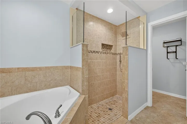 Bathroom featuring a walk in shower, a garden tub, light tile patterned flooring, and recessed lighting