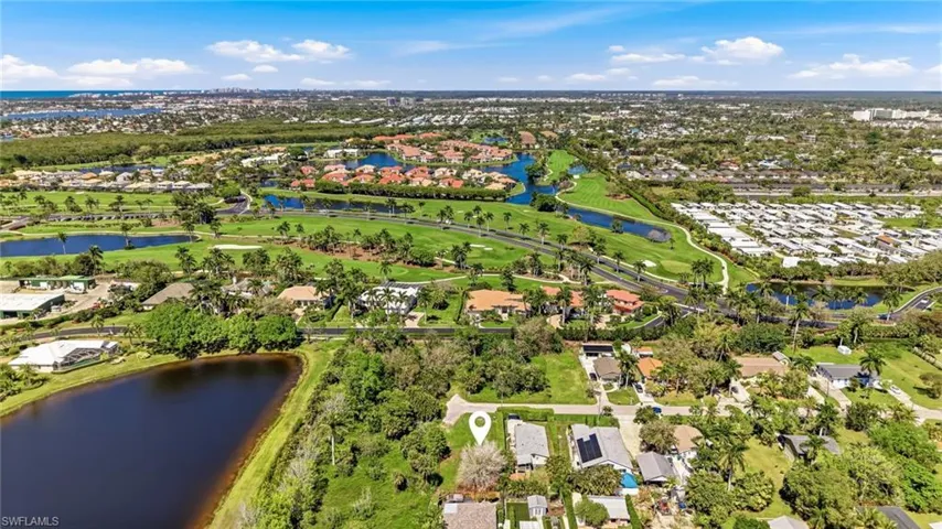 Aerial perspective of suburban area featuring a nearby body of water and a golf club
