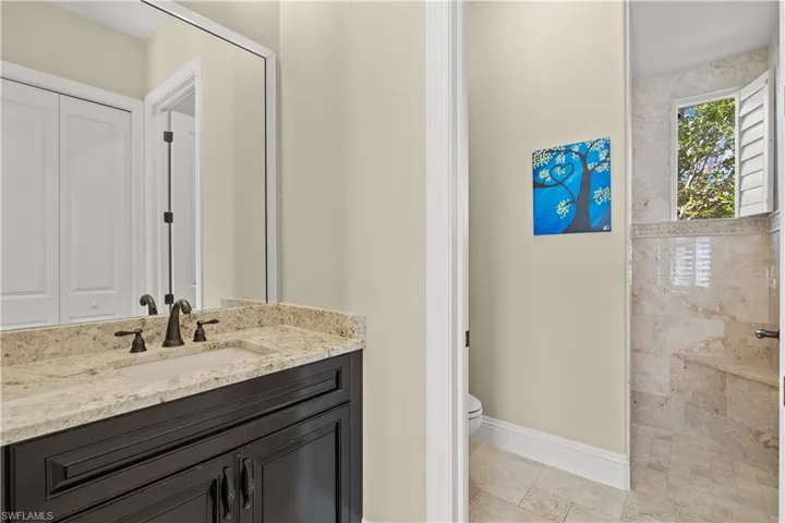 Bathroom featuring a tile shower, vanity, and toilet