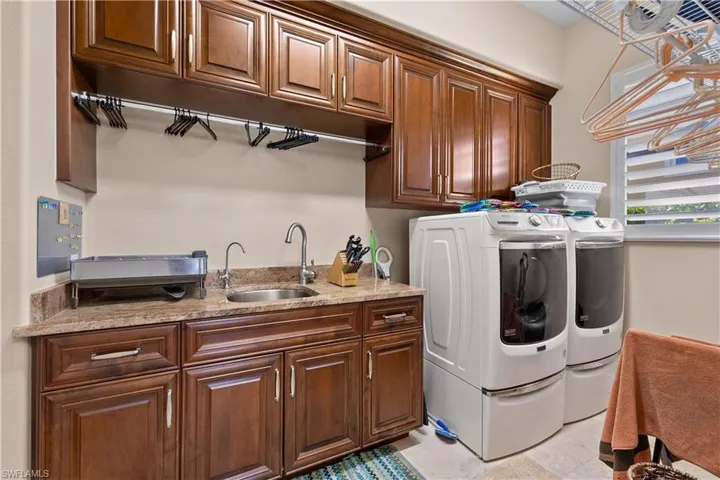 Clothes washing area with cabinets, washing machine and dryer, and sink