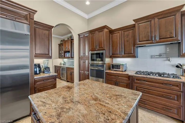 Kitchen with tasteful backsplash, built in appliances, and light stone counters