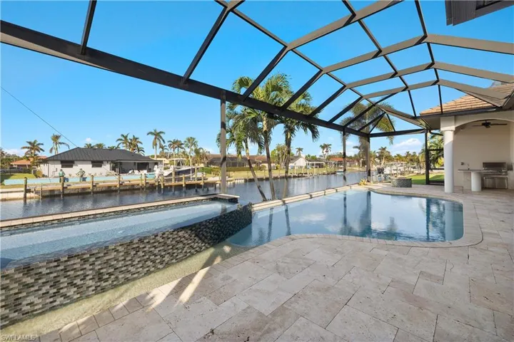 View of swimming pool with an outdoor kitchen, a water view, a patio, and a lanai