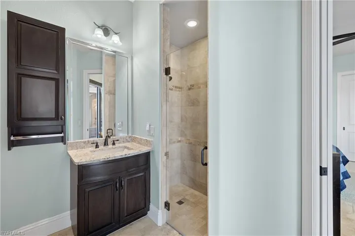 Bathroom featuring tile patterned floors, a shower with door, and vanity