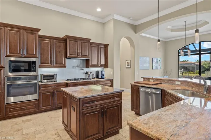 Kitchen with light stone counters, sink, a kitchen island, and stainless steel appliances
