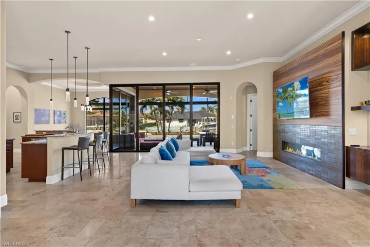 Living room featuring ornamental molding, a tiled fireplace, and a chandelier