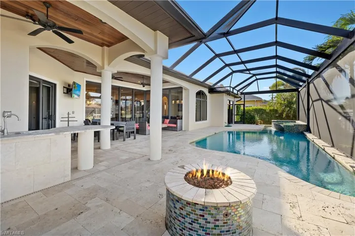 View of pool featuring glass enclosure, ceiling fan, an in ground hot tub, a bar, and a patio