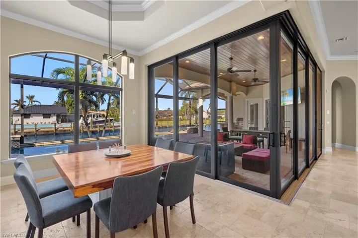 Dining room with ceiling fan, a towering ceiling, a water view, and ornamental molding