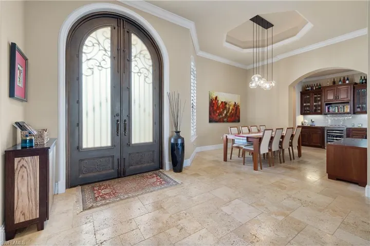 Entryway featuring french doors, wine cooler, ornamental molding, and a notable chandelier