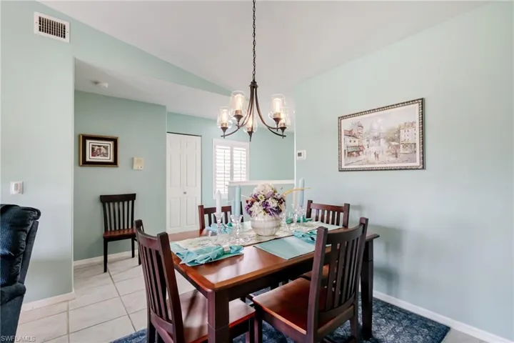 Dining area with vaulted ceiling, a chandelier, and light tile patterned floors