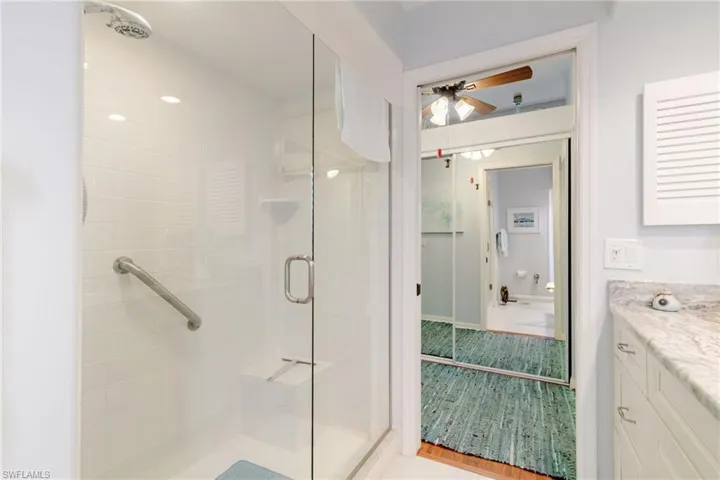 Bathroom with vanity, a stall shower, and a ceiling fan