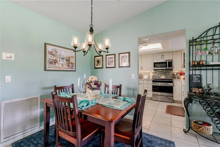 Dining space with vaulted ceiling, light tile patterned floors, and a chandelier