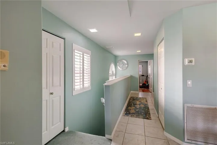 Hall featuring an upstairs landing and light tile patterned floors