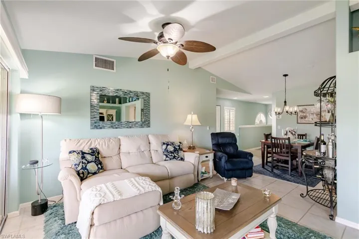 Living room featuring tile patterned flooring, ceiling fan, and a chandelier