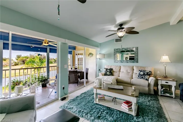 Living area with vaulted ceiling, light tile patterned floors, and a ceiling fan