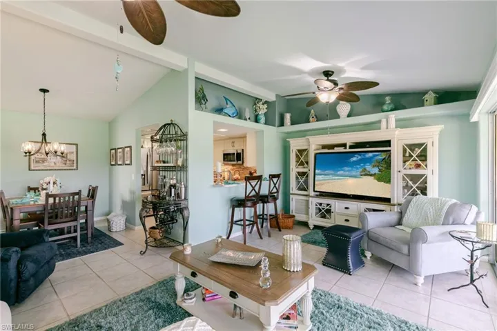 Living area featuring light tile patterned floors, a ceiling fan, and a chandelier