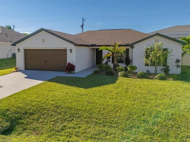 Ranch-style house with stucco siding, concrete driveway, a front yard, and an attached garage
