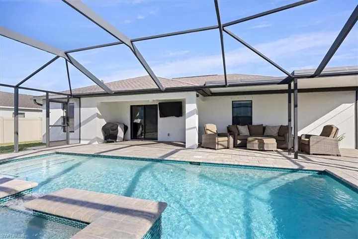 Outdoor pool with a sunroom, glass enclosure, grilling area, and a patio