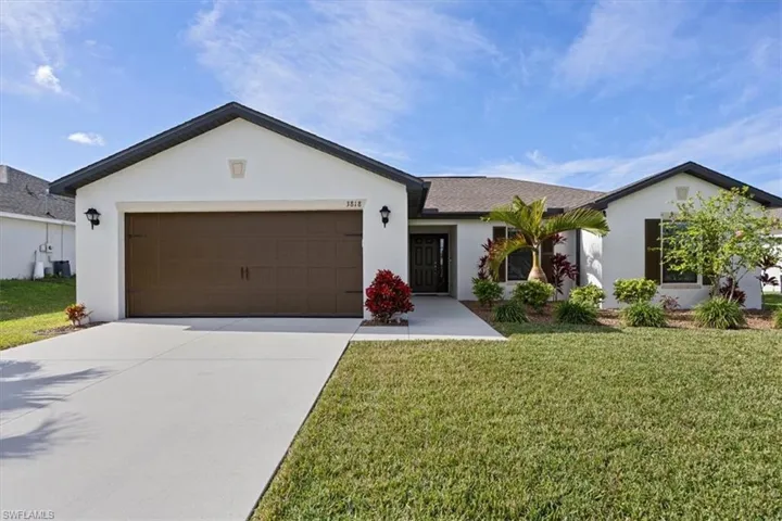 Ranch-style home with stucco siding, an attached garage, a front yard, and concrete driveway