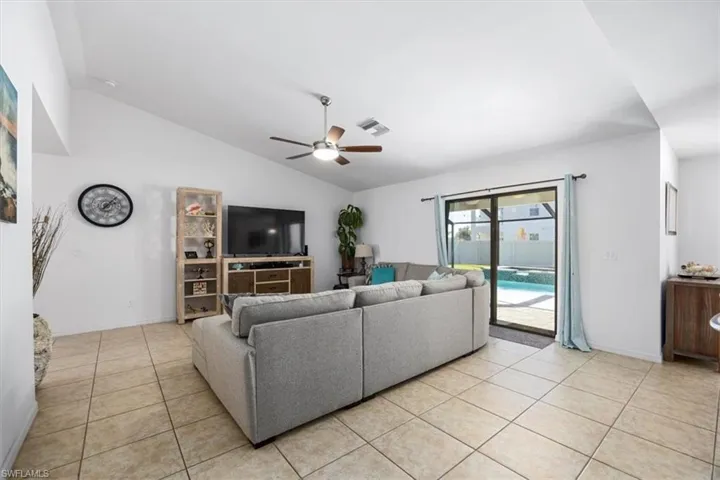 Living area with lofted ceiling, ceiling fan, and light tile patterned floors