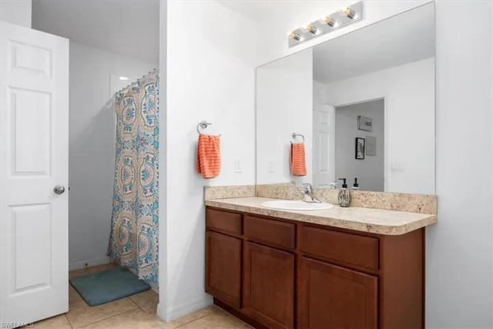 Bathroom featuring curtained shower, vanity, and light tile patterned floors