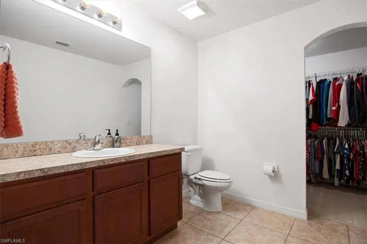 Bathroom featuring a spacious closet, vanity, and light tile patterned flooring