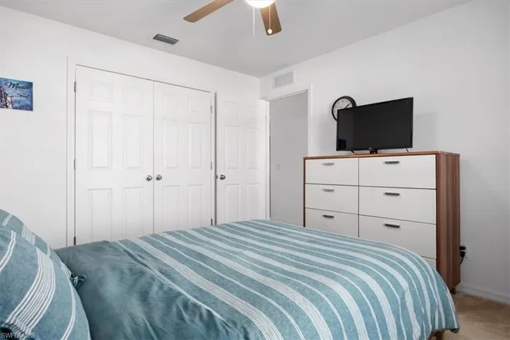 Bedroom featuring light carpet, a ceiling fan, and a closet
