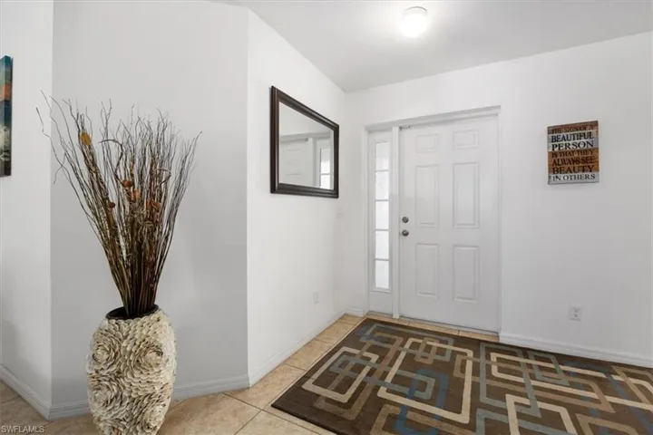 Foyer entrance with light tile patterned floors and baseboards
