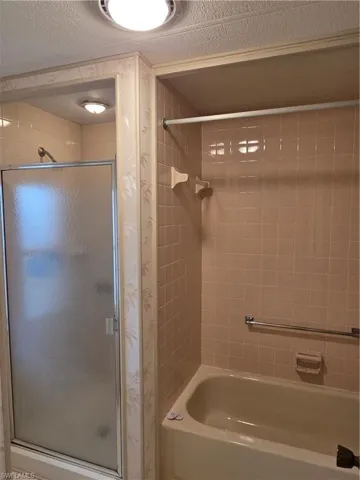 Bathroom featuring a separate shower stall with a frosted glass enclosure and a bathtub with tiled surround