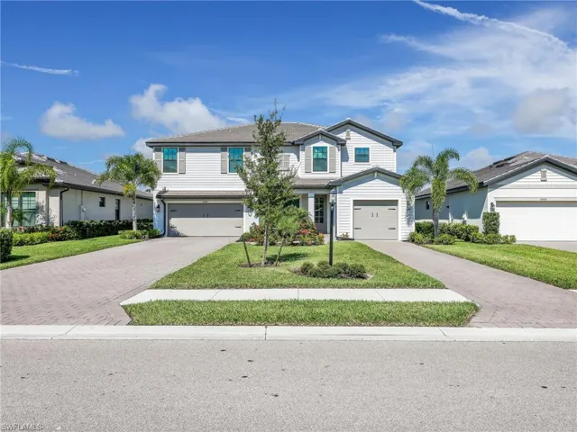 Traditional-style house featuring decorative driveway, a garage, and a front yard