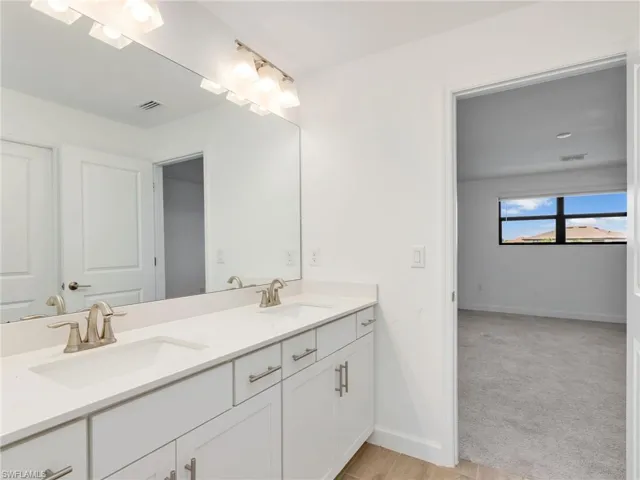 Bathroom featuring double vanity and light carpet