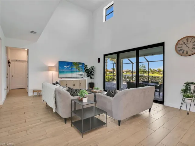 Living room with a sunroom, wood finish floors, and a high ceiling