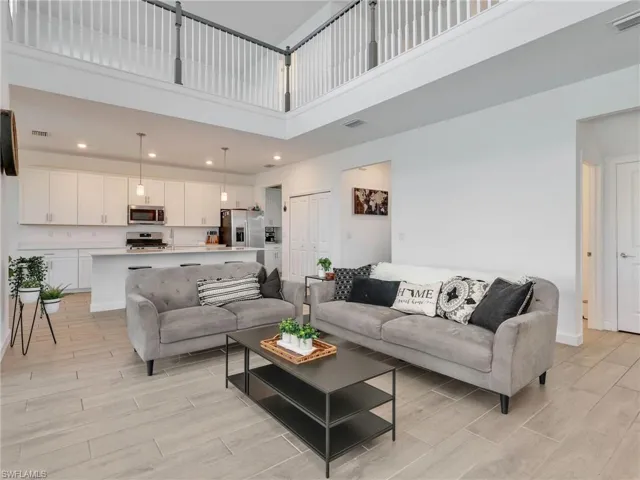 Living area featuring wood finish floors, a high ceiling, and recessed lighting