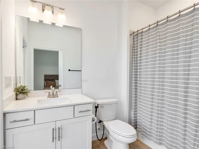 Ensuite bathroom with vanity, a shower with shower curtain, and light wood-type flooring
