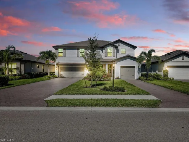 Traditional-style house featuring decorative driveway, an attached garage, and a yard