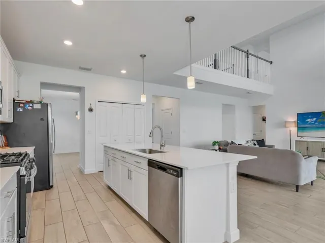 Kitchen featuring white cabinetry, wood tiled floors, stainless steel appliances, and pendant lighting