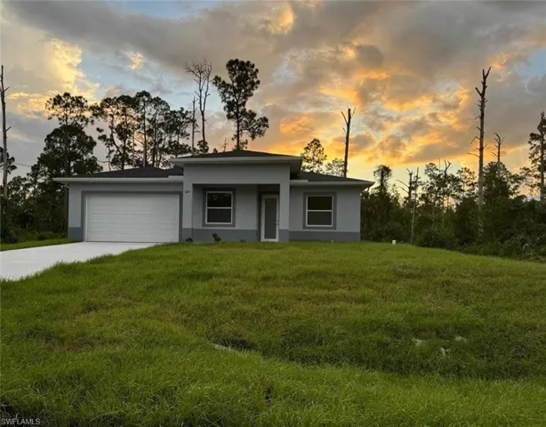 Prairie-style home featuring stucco siding, a garage, driveway, and a front lawn