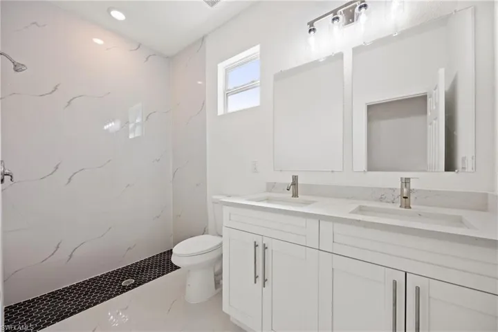 Bathroom with a tile shower, vanity, and toilet