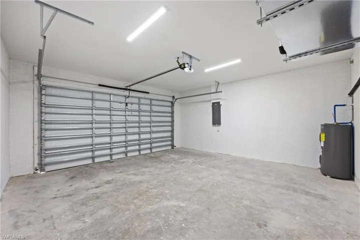 Garage with electric panel, electric water heater, and a garage door opener