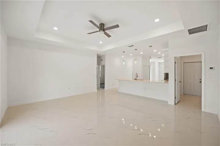 Unfurnished living room featuring ceiling fan, a raised ceiling, and sink