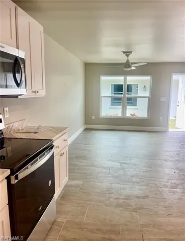Kitchen featuring plenty of natural light, stainless steel appliances, white cabinetry, and ceiling fan