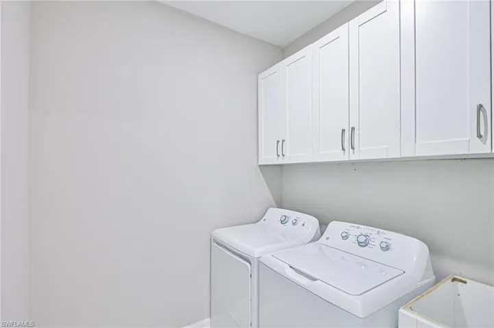 Laundry room featuring independent washer and dryer and cabinets