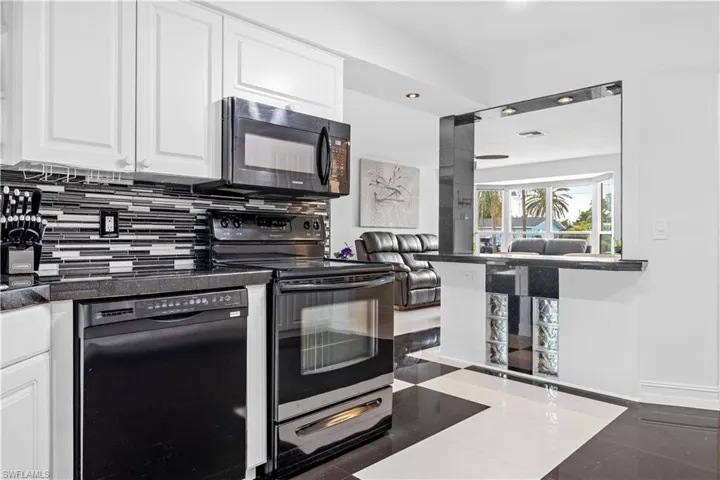 Kitchen featuring tasteful backsplash, white cabinetry, and black appliances