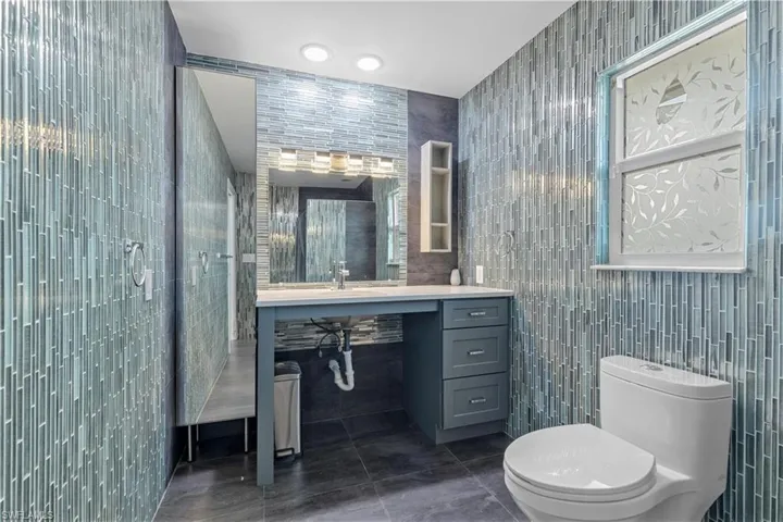 Bathroom with tile patterned flooring, toilet, tile walls, and sink