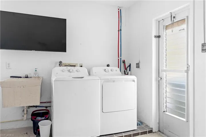 Clothes washing area featuring sink and independent washer and dryer