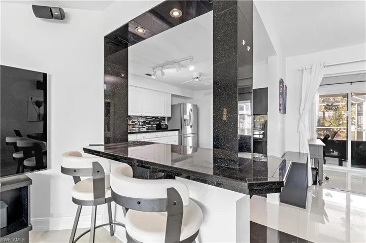 Bar featuring decorative backsplash, stainless steel fridge, white cabinetry, and ceiling fan