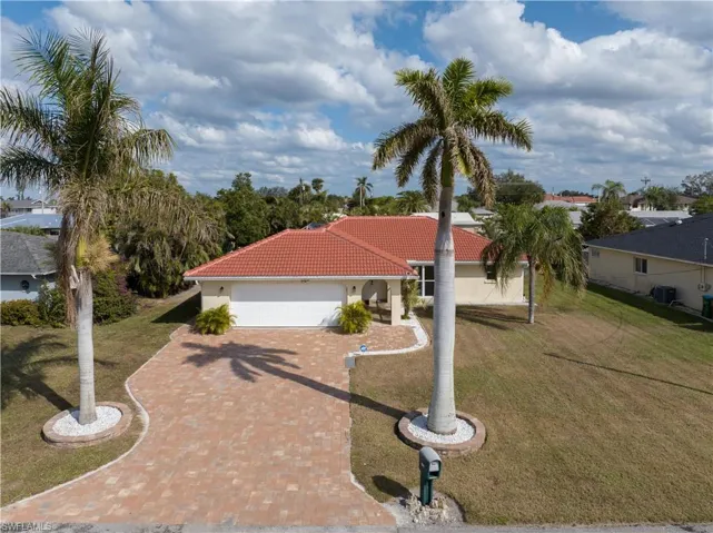 View of front of house featuring central AC unit, a garage, and a front lawn