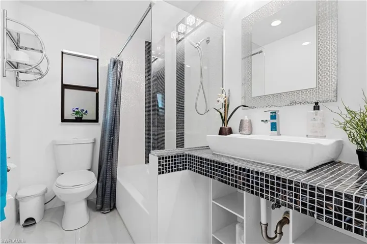 Full bathroom featuring toilet, sink, and shower / tub combo with curtain