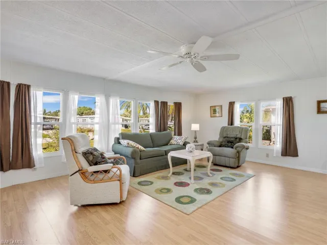 Living area with light wood-style floors, a ceiling fan, and wood walls