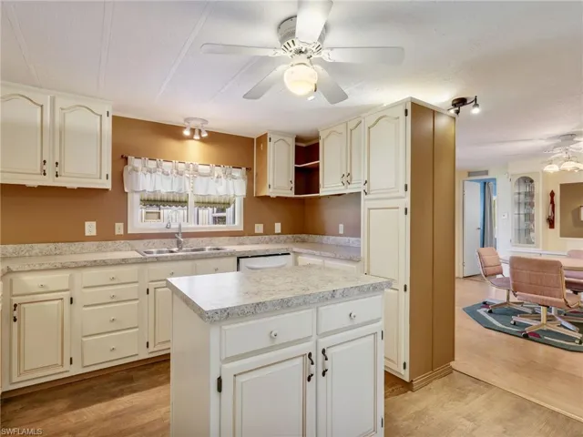 Kitchen with ceiling fan, light countertops, a center island, light wood finished floors, and a textured ceiling